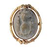 A lava cameo brooch. The grey-tone lava carved to depict a Bacchante, with vine leaves through her h