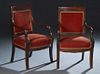 Pair of French Empire Style Carved Walnut Armchairs, 19th c., the wide crest rail over an upholstered back to curved arms with dolphin fish supports, 