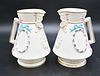 Pair of Belleek Painted Florence Jugs, having wreath and bows, mask form spout, having black mark, height 7 1/2 inches. Provenance: Collections of Nor