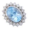 A topaz and diamond cluster ring. The oval-shape blue topaz, within a brilliant-cut diamond surround