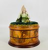 Artisan designed sewing box. 9 1/2" high overall, china half doll tops oval box with art nouveau design, opens to reveal two inner compartments that h