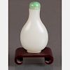 A White Jade Snuff Bottle with Green Jade Stopper on Carved Hardwood Stand.