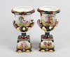 A pair of Vienna porcelain urns, each having twin short scrolled handles and raised upon stepped ped