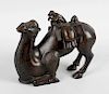A bronze figure, modelled as a camel in half seated position having loaded saddle and monkey rider,