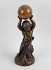 A late 19th century bronze study of a putto with hand held aloft, holding a marble sphere, seated up