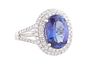 Lady's Platinum Dinner Ring, with a 4.24 ct. oval tanzanite, atop a double graduated concentric border of tiny round diamonds, the split shoulders of 