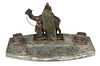 Bergman Style Cold Painted Spelter Arabic Inkwell, early 20th c., with an Arab rug merchant and camel behind two lidded inkwells with white porcelain 