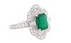 Lady's 18K White Gold Dinner Ring, with a 1.56 ct. emerald, atop a shaped border of small round diamonds flanked by diamond mounted lugs and a conform