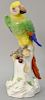 Large Meissen porcelain parrot having bright plumage perched on a floral decorated tree stump having blue crossed swords mark "A43A"...