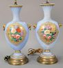 Pair of porcelain vases made into table lamps, each powder blue with raised gilt decoration, hand painted floral panels, and metal m...