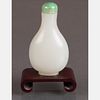 A White Jade Snuff Bottle with Green Jade Stopper on Carved Hardwood Stand,