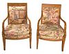 Pair of French Empire style chairs The fruitwood open arm chairs carved with dolphin arm rests, raised on four splayed legs, now over upholstered with