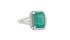 Lady's Platinum Dinner Ring, with a 4.79 ct. emerald atop a border of small round diamonds, the splits shoulders of the band also mounted with small r
