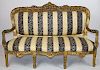 Louis XV style gilt parlor settee with striped silk upholstery.