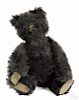 Black mohair teddy bear with elongated limbs and snout, felt pads, and stick pin glass eyes