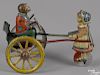 Gama tin lithograph lever action monkey in a cart toy, being pulled by a young girl