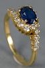 18K gold ladies ring set with center oval sapphire surrounded by diamonds.