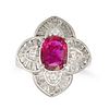 A RUBY AND DIAMOND CLUSTER RING in platinum, set with an oval cut ruby of 1.31 carats in a stylis...