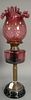 Cranberry art glass lamp with ruffle top shade.