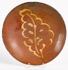 Redware plate, 19th c., with yellow slip leaf decoration, 10'' dia.
