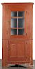 Painted pine one - piece corner cupboard, 19th c., retaining an old red surface, 83'' h., 39'' w.
