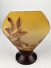 Galle cameo vase with dark and light brown leaves on a ellow ground.