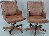 Pair of Councill leather armchairs having swivel bases.