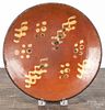 Pennsylvania redware plate, ca. 1800, with slip decorated dots and triple wavy lines, 10'' dia.