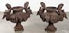 Pair of cast iron putti and rams head garden urns