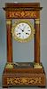 Rosewood empire mantle clock with marquetry inlays, porcelain dial with gilt surround, and brass pendulum