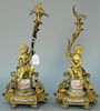 Pair of French gilt bronze candle holders mounted with putti on base with porcelain panels, one made into lamp. 
ht. 17in. Pr