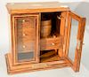 Oak inlaid cigar cabinet having two glass doors opening to fitted drawer interior and tobacco jar. ht. 15in., wd. 15 1/2in.,