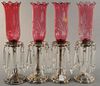 Set of four silverplate hurricane lamps with cranberry etched shades. ht. 20in. Provenance: Property from the Estate of Frank