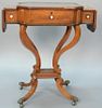 Regency mahogany stand, lift top trimmed with brass around leather surface flanked by drop leaves on four inlaid supports on