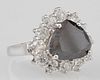 Lady's 14K White Gold Dinner Ring, with a 5.75 carat pear shaped black diamond, atop a conforming border of round diamonds, t