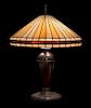 * Miller Lamp Co., EARLY 20TH CENTURY, a leaded glass table lamp, having a conical geometric shade raised on an urn-form base