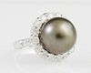 Lady's 14K White Gold Dinner Ring, with a 12.5 mm black Tahitian pearl atop a border of round diamonds, the shoulders of the 