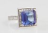 Lady's 14K White Gold Dinner Ring, with an emerald cut 4.25 carat tanzanite, atop a border of round white diamonds, the shoul