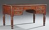 English Victorian Carved Walnut Desk, 19th c., the rounded edge stepped corner top with an inset gilt tooled leather writing 