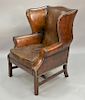 Distressed brown leather wing chair.