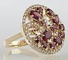 Lady's 14K Yellow Gold Dinner Ring, the pierced top with swirls of rubies and diamonds, within a border of small round diamonds, total ruby weight- 1.