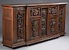 French Carved Oak Sideboard, early 20th c., the stepped breakfront top over two floral carved double panel cupboard doors with iron strap hinges flank