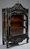 Diminutive French Louis XV Style Ebonized Mahogany Vitrine, late 19th c., the arched floral carved crest over a shaped glazed door with iron butt hing