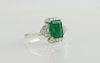 Lady's 18K White Gold Dinner Ring, with a 1.61 carat emerald atop a frame of round diamonds and diamond mounted lugs, total diamond weight- .21 cts., 
