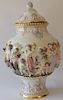 Porcelain urn with cover having three dimensional figures (chip on base and cover). 
height 16 inches 
***If this lot is not picked ...
