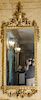 Continental style gilt mirror with urn top and large flowers (some old repairs). 
height 81 inches, width 34 inches 
***If this lot ...