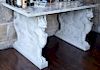 Marble table having mottled purple marble top set on base of double sided carved carrara marble winged griffins. 
height 35 inches, ...