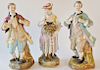 Group of four porcelain figures including a Meissen blacksmith working, two Colonial men holding flowers, and a woman with a bouquet...