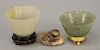 Three Chinese jade pieces to include small celadon cup on hardwood stand, a russet jade double foo dog, and spinach green jade cup o...
