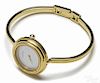 Lady's Gucci wristwatch with a gold-tone round case, bangle band, and a white face